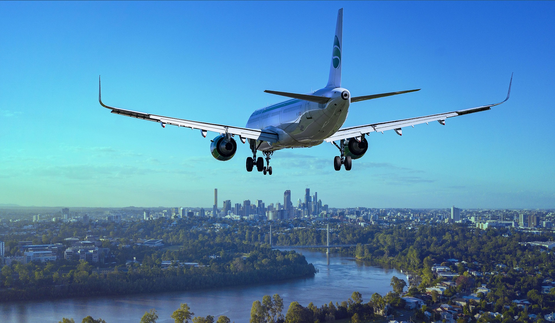 Airplane in sky getting ready to land with city in distance