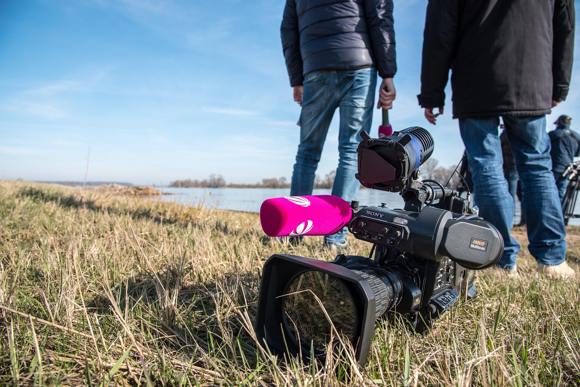Press media in field with large camera on ground